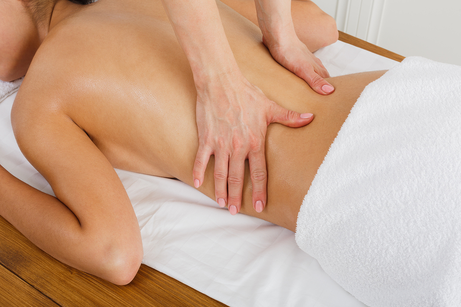 Hands Touching Bare Waist Area of Female Laying on Table