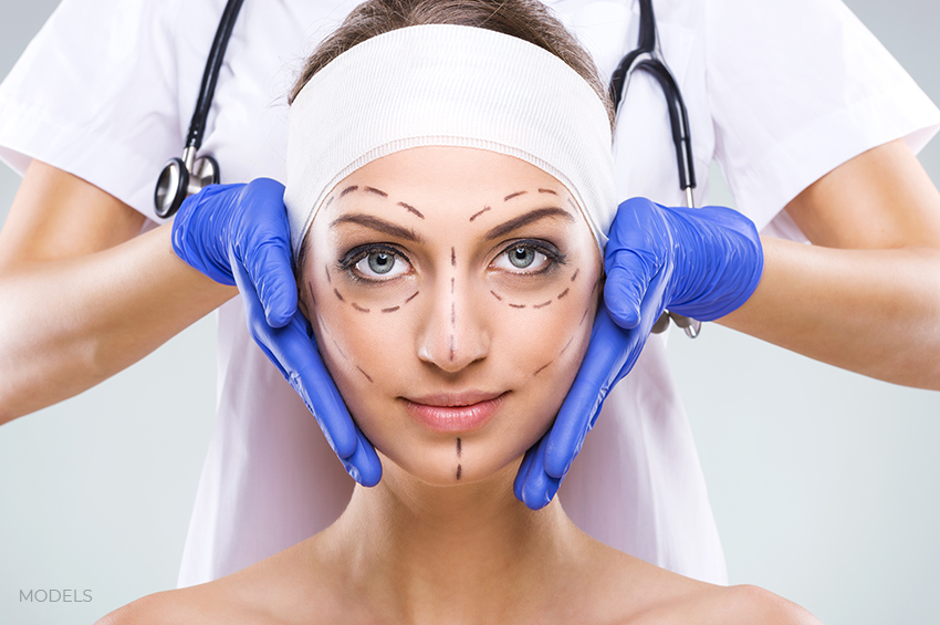 Female on plastic surgery office with marked lines on face